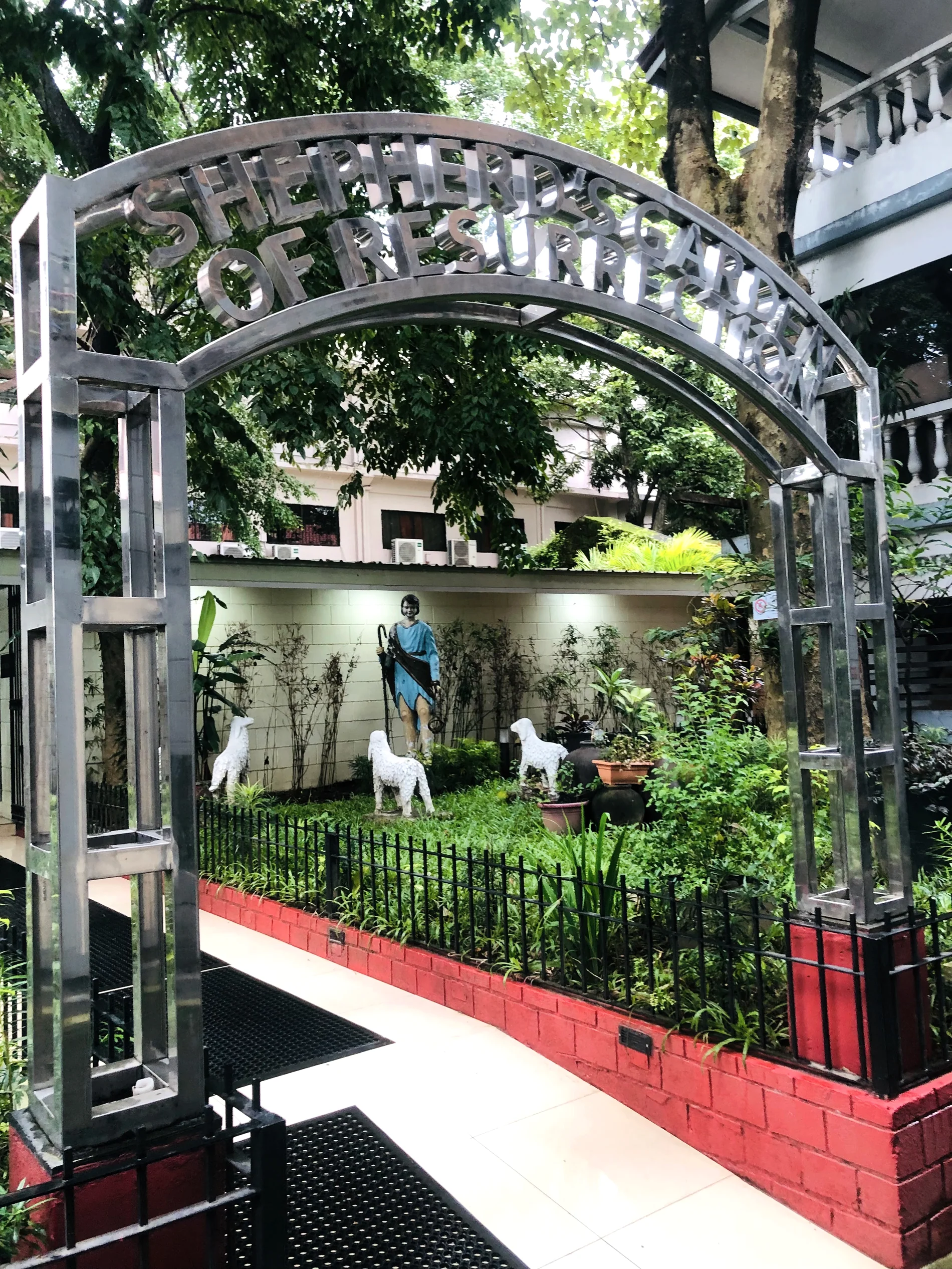 Good Shepherd garden arch surrounded by greenery