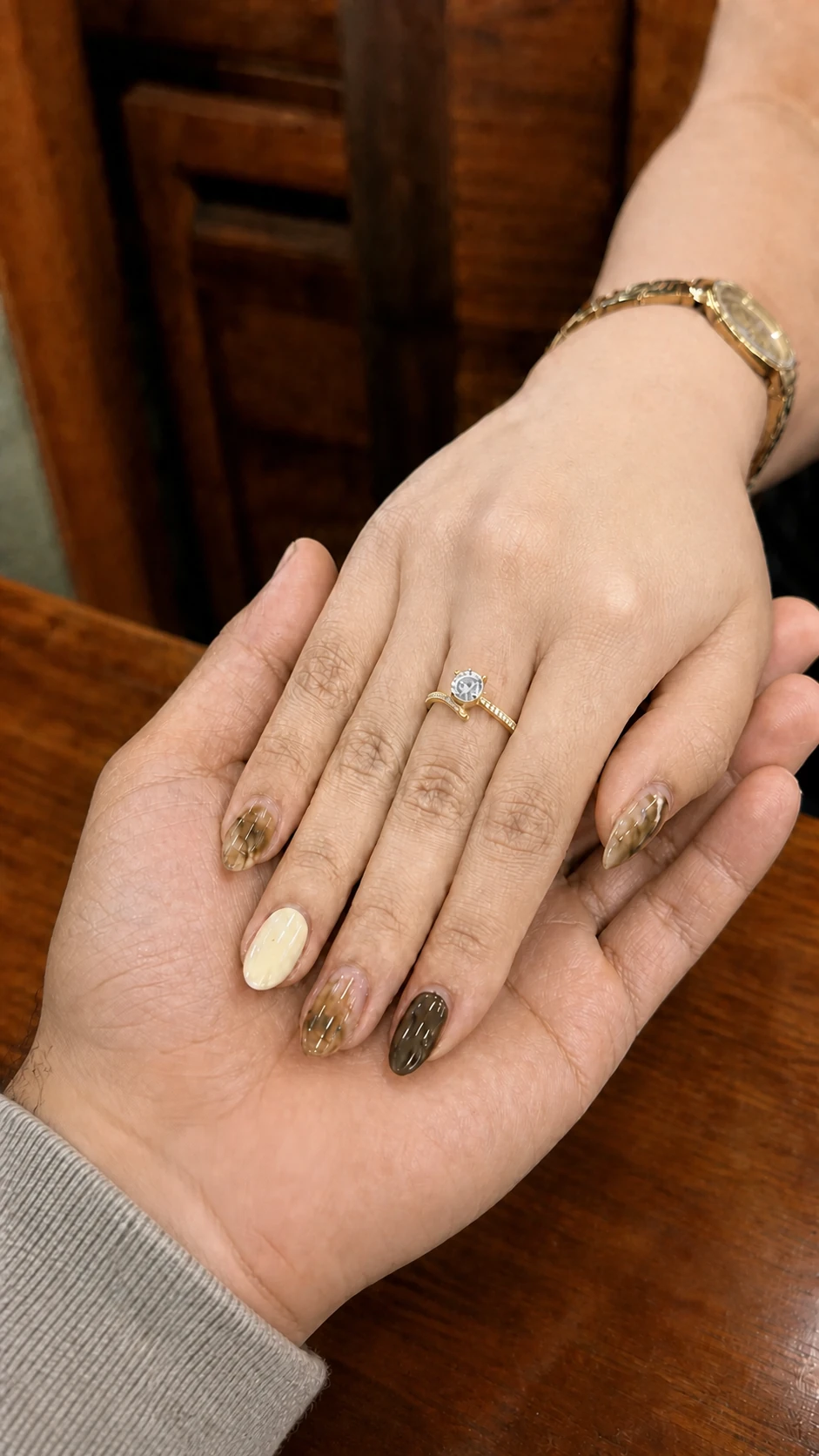 Maila's engagement-ring hand resting in Carlo's right hand